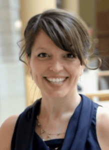 Christine Stephenson smiles for her bio photo. In this photo, she has brown hair and is wearing navy blue.