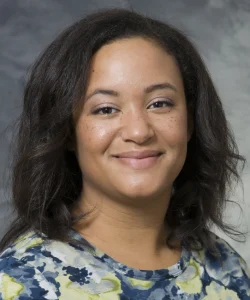 Andrea Gilmore Bykovskyi smiles for her bio picture. She has medium length black hair, and she wears a floral top.