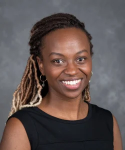 Shenell Edwards is smiling and wears a black top. She has long ombre dreads.