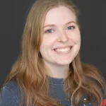 Brittney smiles for her bio photo. She has long chestnut colored hair and wears a NASA shirt.