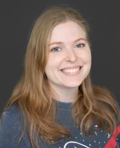 Brittney smiles for her bio photo. She has long chestnut colored hair and wears a NASA shirt.