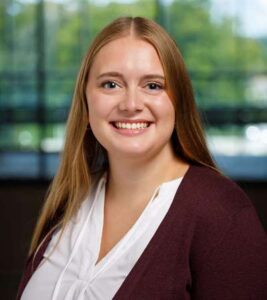 Abby Rudd smiles for her bio picture. She has long, light brown hair and wears a white blouse and black blazer.